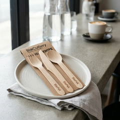 4 in 1 compostable wooden cutlery pack components displayed on a table showcasing the smooth finish and 2 ply kraft napkin.