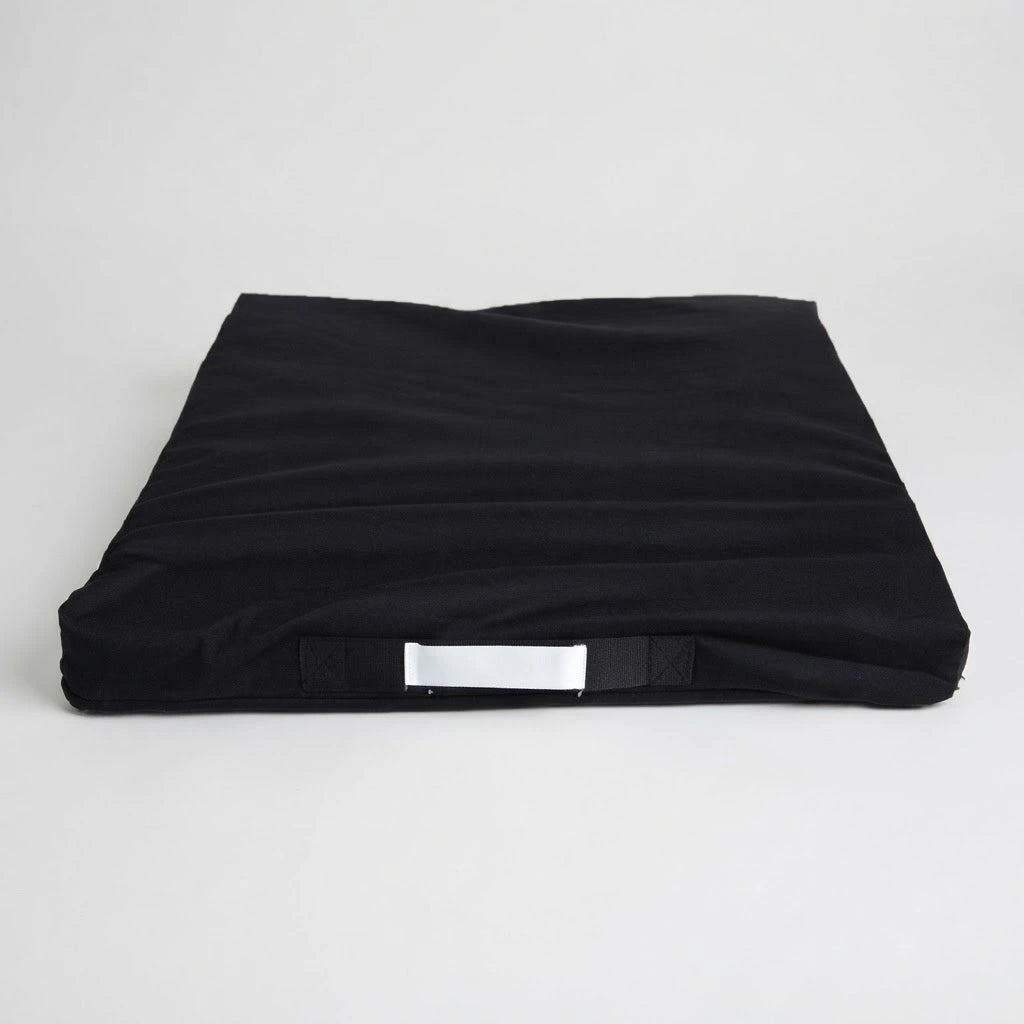 Underside of a black fabric seat cushion cover showing the non-slip base and white fabric carrying handle.