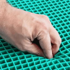 Close-up macro shot of a hand squeezing a square-cell teal gel grid seat cushion